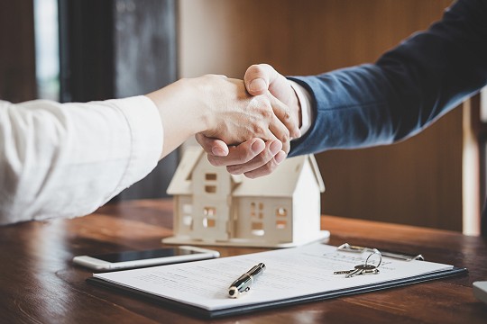 Real estate agent and customer shaking hands celebrating finished real estate loan contract